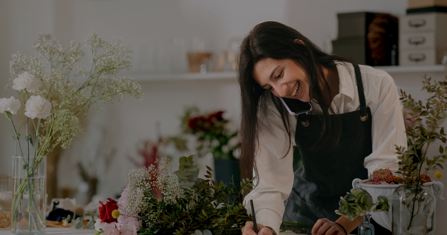 Woman on the phone, behind the counter of a florist