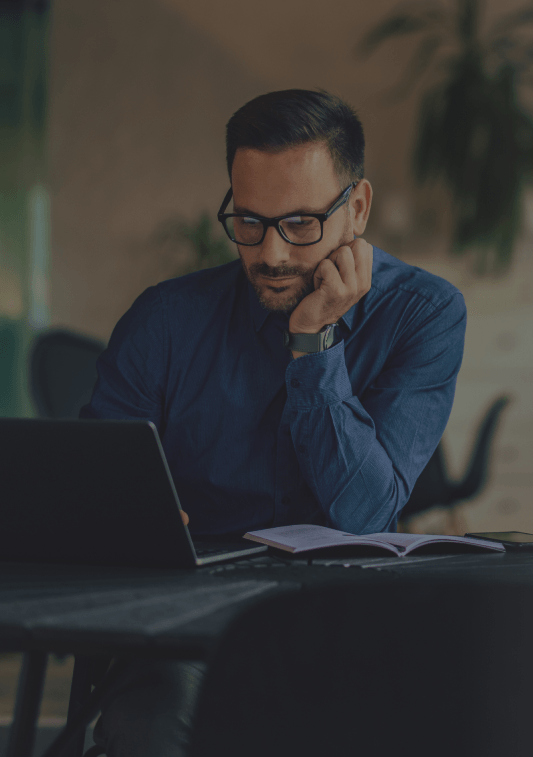 Man sitting at a desk, looking at a laptop
